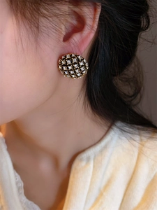 Gros plan de boucles d'oreilles dorées et noires avec cristaux portées par un mannequin