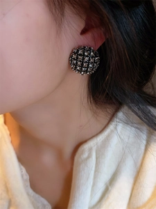 Gros plan sur les boucles d'oreilles rondes dorées avec grille et strass scintillants