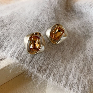 Nahaufnahme geometrischer Glasohrringe mit champagnerfarbenen Steinen in mattem Goldrahmen