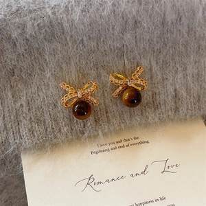 Gros plan des boucles d'oreilles œil de tigre avec nœud en zircon sur tricot gris