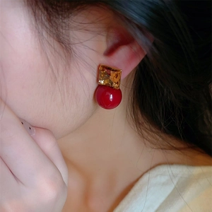 Detailed view of red square crystal and pearl drop earrings worn on a female model