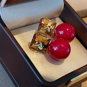 Detailed close-up of sugarloaf crystal and red pearl earrings in a velvet jewelry box