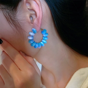 Detail of macaron beaded hoop earrings in blue and purple on model's ear