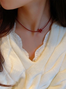 Close-up of red bead necklace with a matching five-petal flower pendant on a model