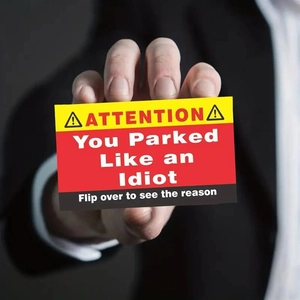Close-up of funny bad parking warning cards with creative you parked like an idiot text