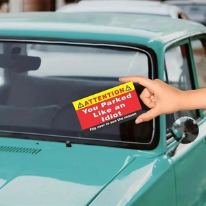 Detail of creative 'You Parked Like an Idiot' prank card on a vintage car windshield