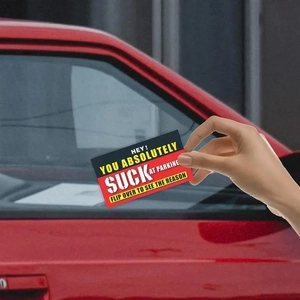 Close-up of a hand placing a sarcastic parking violation card on a car window
