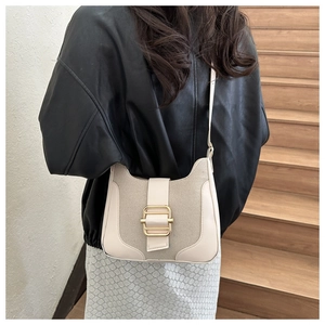 Détail du tissage beige et de la boucle en métal doré d'un sac à bandoulière
