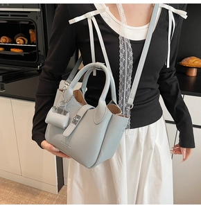 Detail van lichtblauwe leer emmer tas met lychee patroon, zilver slot en kleine pouch