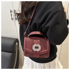 Burgundy faux leather crossbody bag with sparkling rhinestone buckle shown on model
