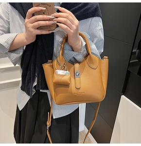 Detail van de mosterdgele leren emmertas met metalen slot en Fashion Bags logo-opdruk