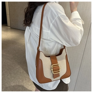 Détail du sac à bandoulière en toile vintage et cuir marron avec boucle en métal doré
