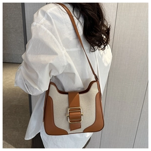 Détail du sac à bandoulière en toile avec finitions en cuir brun et boucle dorée