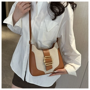 Détail du sac bandoulière rétro en toile et cuir marron avec boucle dorée sur chemise