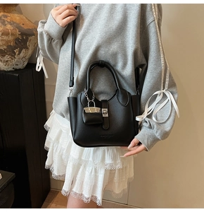Detail van zwarte litchi lederen bucket bag met zilveren sluiting getoond door een model