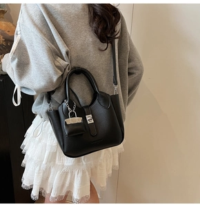 Detail van de zwarte bucket bag van generfd leer met zilveren draaisluiting en mini-tas