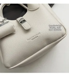 Detail van crème lederen tas met lychee textuur, zilveren drukknoop en zachte afwerking