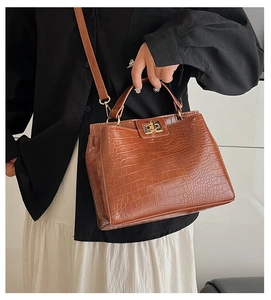 Detail of vintage brown crocodile embossed leather handbag with metal turn-lock closure