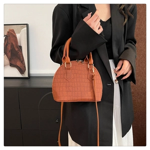 Detalle de bolso marrón con textura de cocodrilo y cremalleras doradas de moda