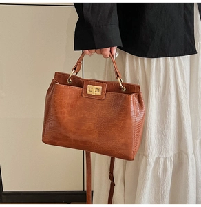 Macro detail of brown crocodile pattern leather handbag with golden twist lock closure