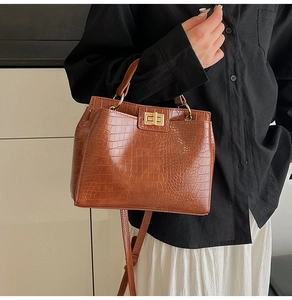 Detail of vintage brown crocodile texture bag with gold twist lock and fine PU leather stitching