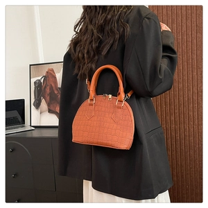 Detalle de bolso de mano marrón con textura de cocodrilo y herrajes dorados elegantes