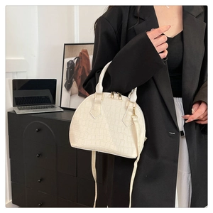 Vista detallada del bolso de mano blanco con forma de concha y relieve de cocodrilo