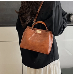 Detail of caramel brown crocodile embossed handbag with a gold twist lock and top handle