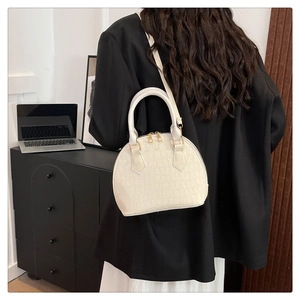 Detalle de bolso blanco con textura de cocodrilo y cremalleras doradas con la modelo