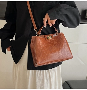 Brown crocodile pattern crossbody bag detail showing gold twist lock and fine texture
