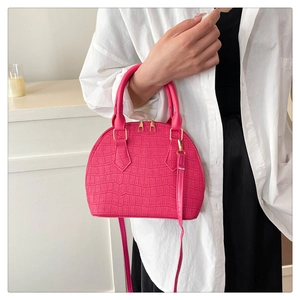Detalle de bolso concha rojo rosa con estampado de cocodrilo, cremallera dorada y asas