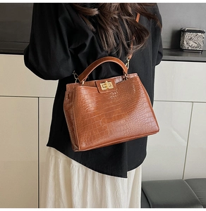 Macro shot of brown crocodile pattern handbag with golden twist lock and luxury PU texture