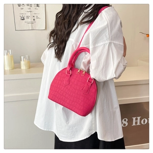 Detalle del bolso fucsia con textura de cocodrilo, cremallera dorada y asas de mano