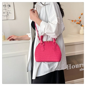 Detalle de bolso concha rosa con textura de cocodrilo y cremallera dorada elegante