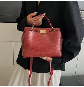 Detail of red crocodile pattern handbag featuring a gold-tone turn-lock and top handle
