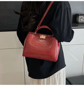 Detail of red faux leather handbag with crocodile pattern and golden metal twist lock