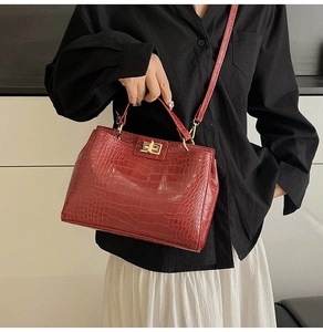 Detail of red crocodile pattern handbag featuring glossy finish and gold square twist lock
