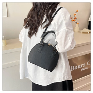 Detalle del bolso tipo concha negro con grabado de cocodrilo y cremalleras doradas de lujo