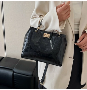 Close-up of black crocodile pattern leather handbag with gold twist lock and shoulder strap