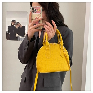 Detalle de bolso amarillo con relieve de cocodrilo, asas dobles y correa de hombro