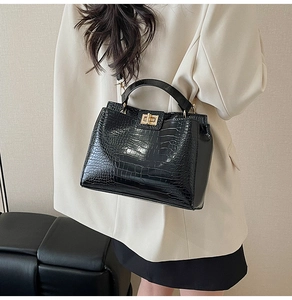 Detail of black crocodile embossed faux leather handbag with gold metal twist lock closure