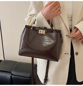 Detail of vintage dark brown crocodile pattern handbag with golden square twist lock
