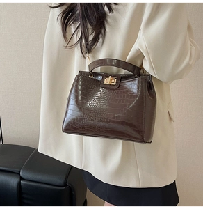 Macro detail of deep brown crocodile embossed leather texture with golden twist-lock buckle
