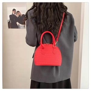 Detalle de bolso rojo con textura de cocodrilo usado como bandolera sobre blazer