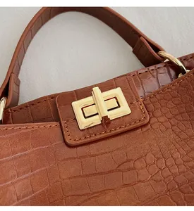 Close-up of golden rotating lock and brown crocodile pattern texture on a leather handbag