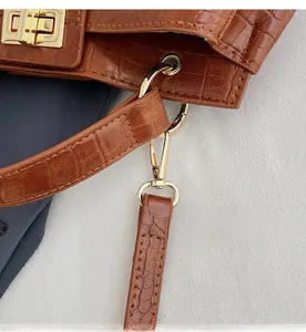 Detail of golden twist lock and lobster clasp on brown crocodile texture handbag