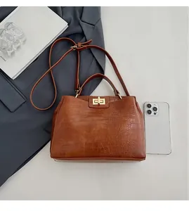Detail of brown crocodile pattern leather handbag with golden metal twist lock and handle