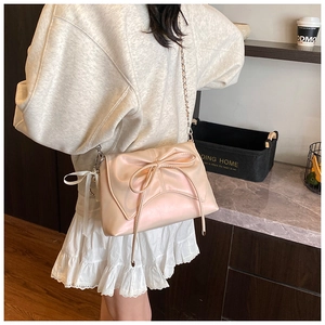 Detail of light pink ballet-style bag with large bow and silver chain strap