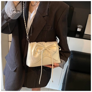 Detail view of the cream-colored bow crossbody bag with elegant leather tassel details