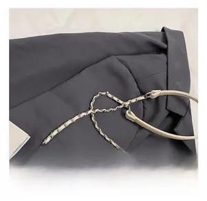 Detail of silver chain strap and polished hardware on a beige pleated ballet bow bag